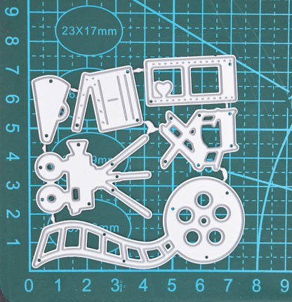 Movie and film themed metal cutting dies displayed on cutting mat showing cinema camera reel and director chair craft designs