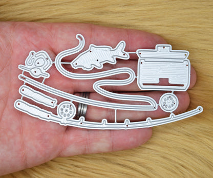 Fishing themed metal cutting dies shown in hand for size reference