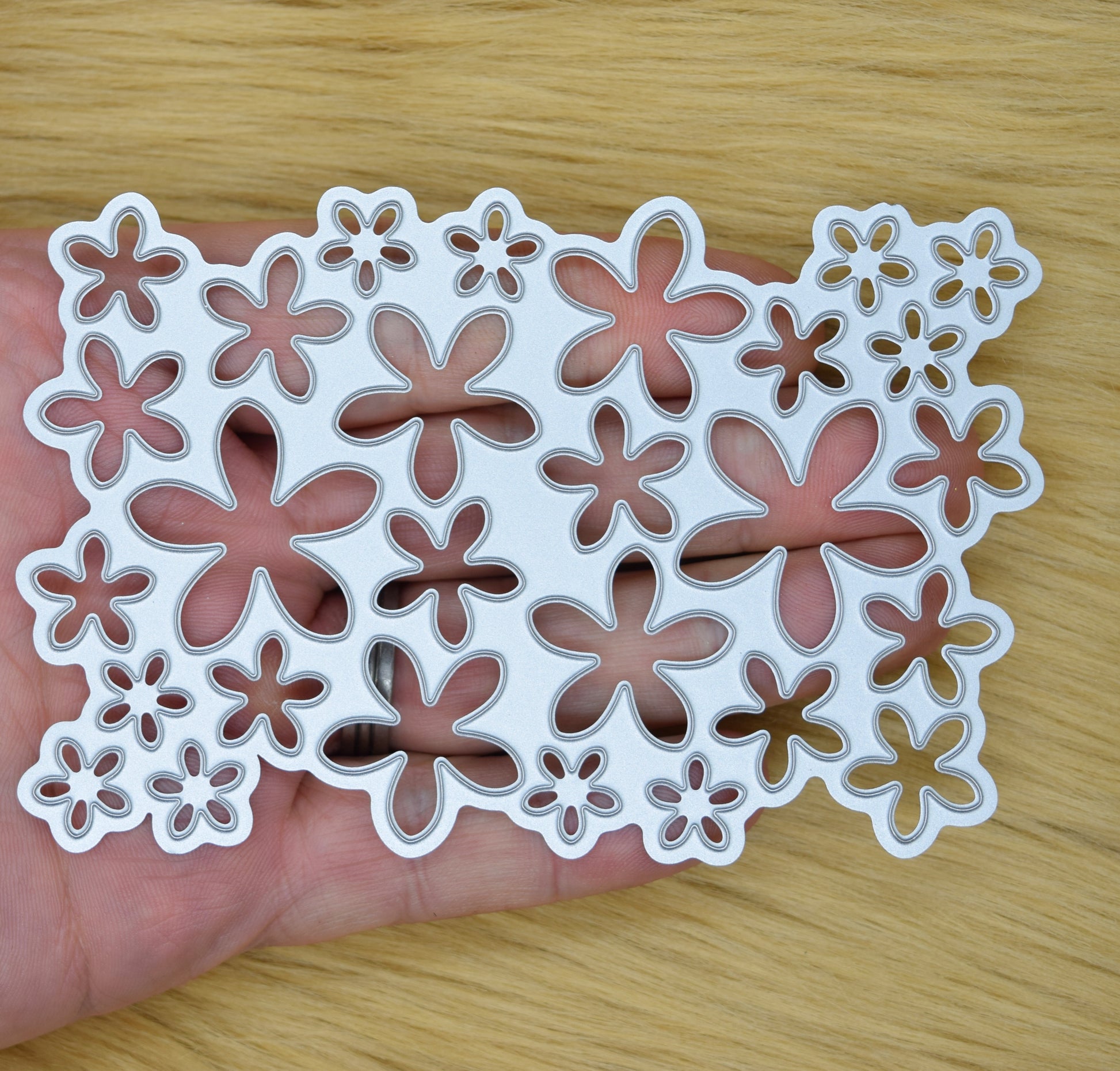 Floral background metal cutting die held in hand showing size