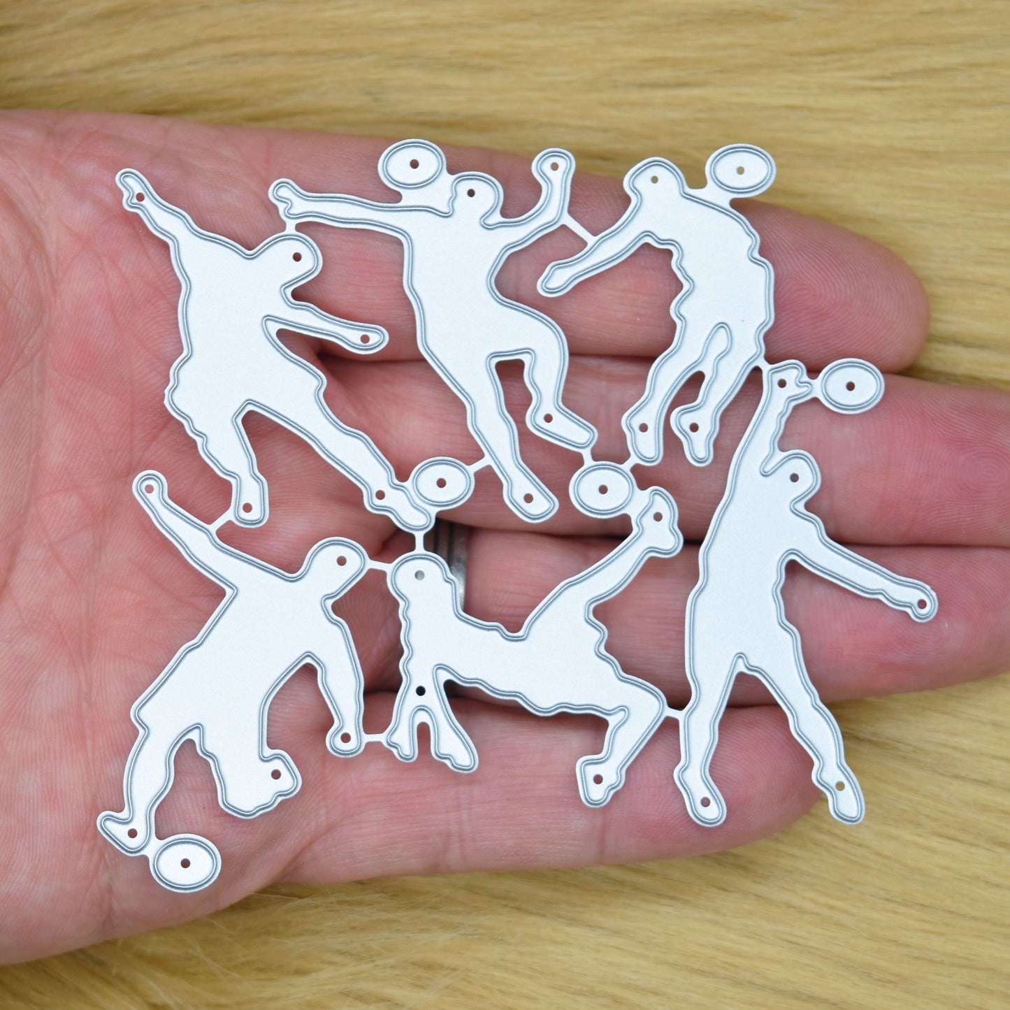 Football player metal cutting dies shown in hand to demonstrate the size of the six-die set
