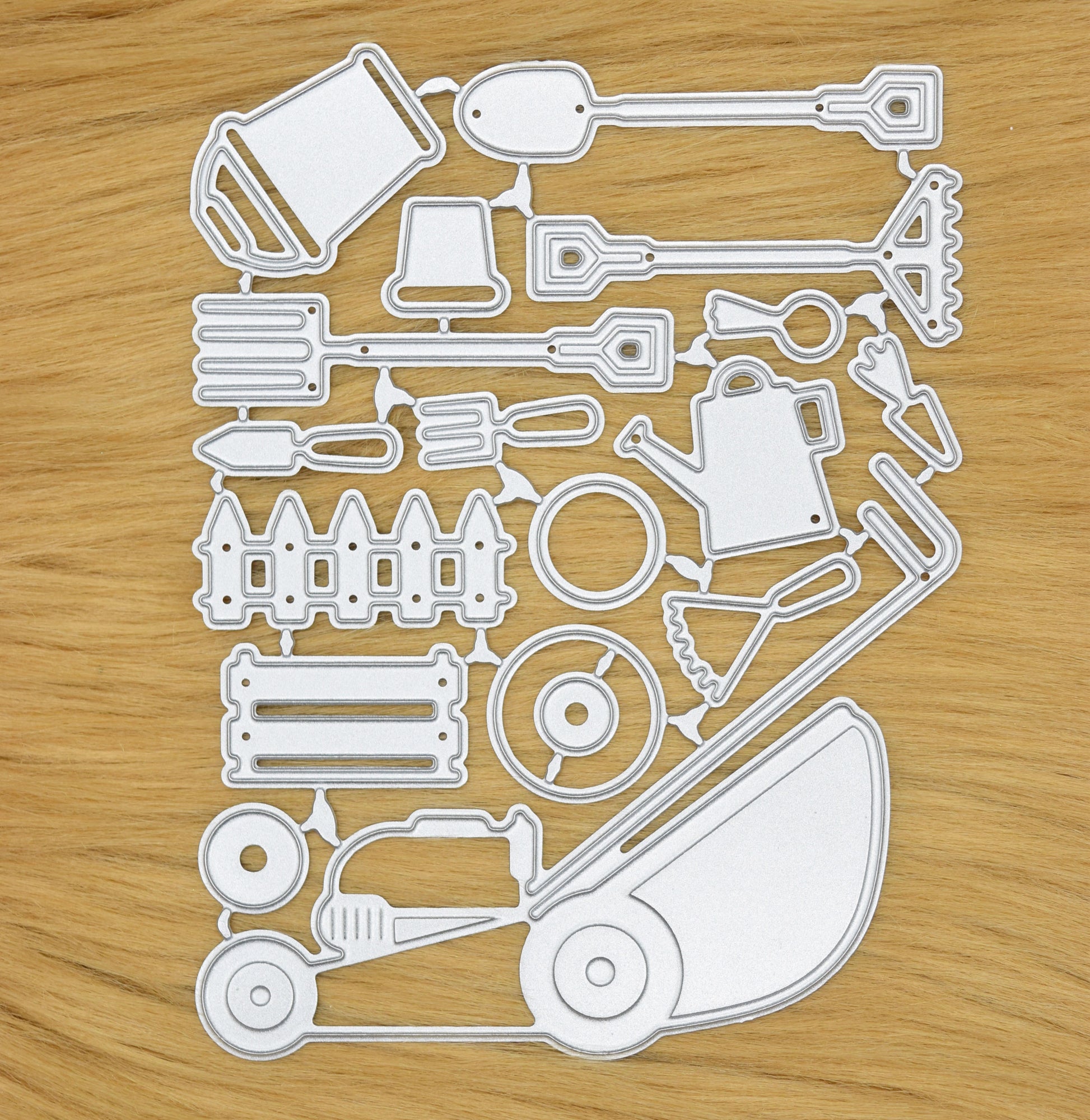 Full gardening tools metal cutting die set arranged on surface showing lawn mower, watering can and garden tools