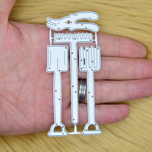 Spade, garden fork, rake and secateurs metal cutting dies held in a hand to show their overall size.