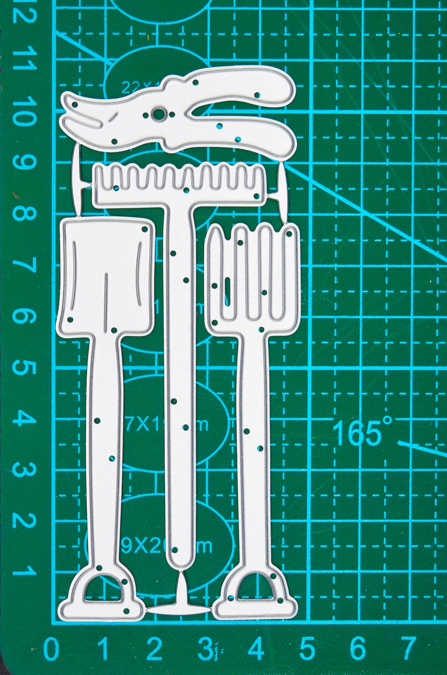 Gardening tools metal cutting dies featuring a spade, fork, rake and secateurs displayed on a centimetre cutting mat.