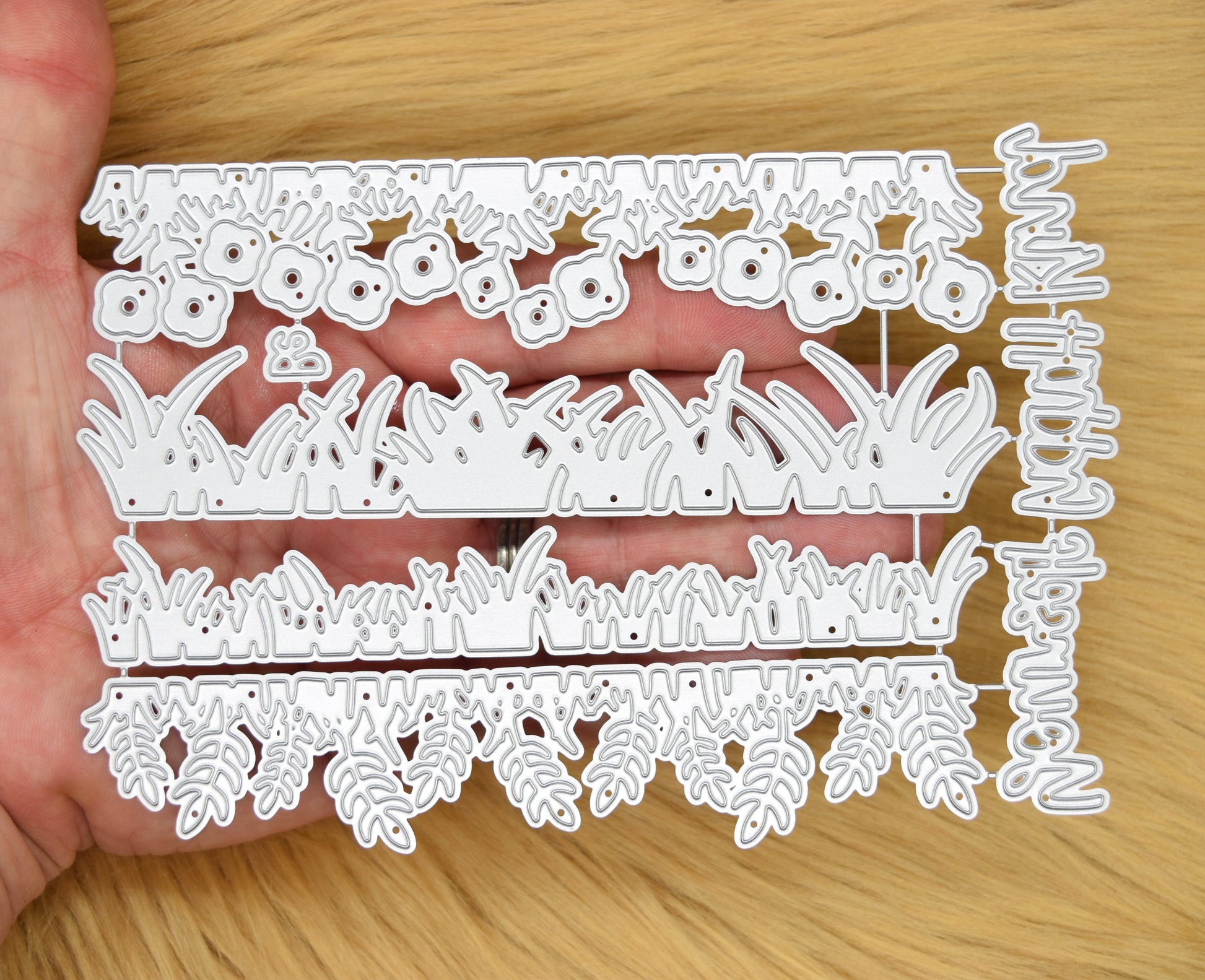 Grass border edging metal cutting dies shown in hand for papercraft and card making