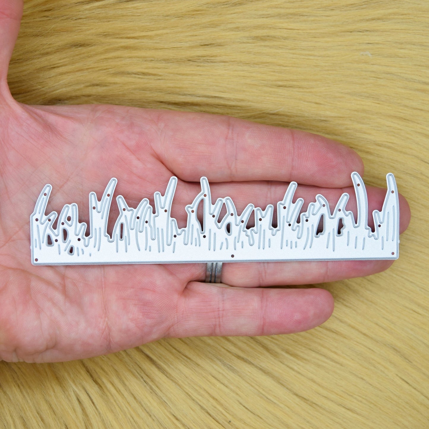 Grass border metal cutting die held in hand to show the size and detailed blade design