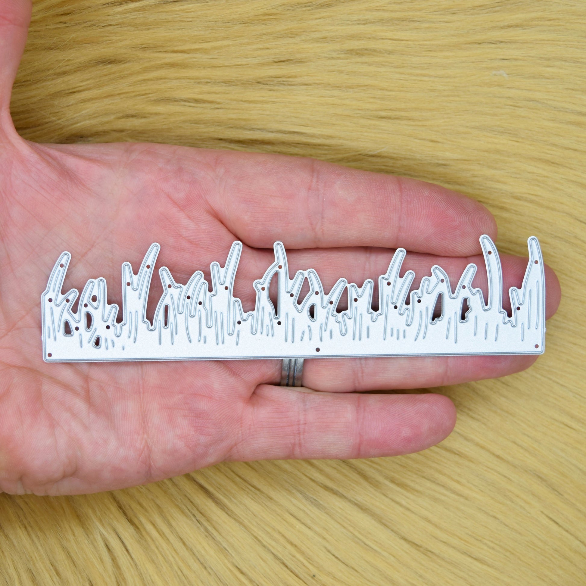 Grass border metal cutting die held in hand to show the size and detailed blade design