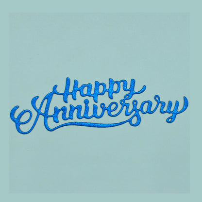 Blue glitter Happy Anniversary script die cut showing the flowing underline and decorative handwritten lettering.