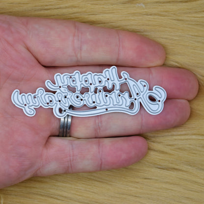 Happy Anniversary script metal cutting die held in a hand to demonstrate its overall size.