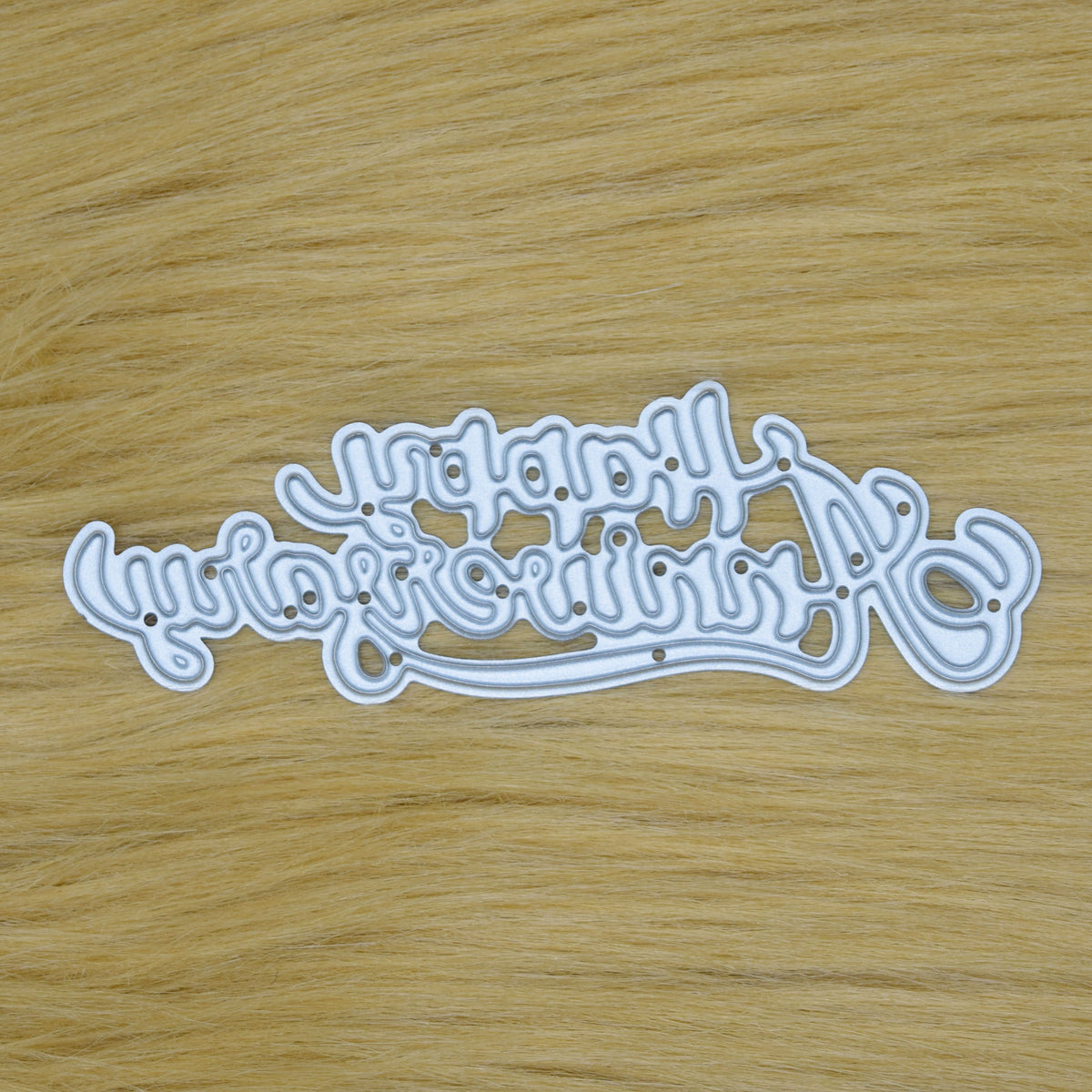 Happy Anniversary script sentiment metal cutting die displayed on a faux fur background.