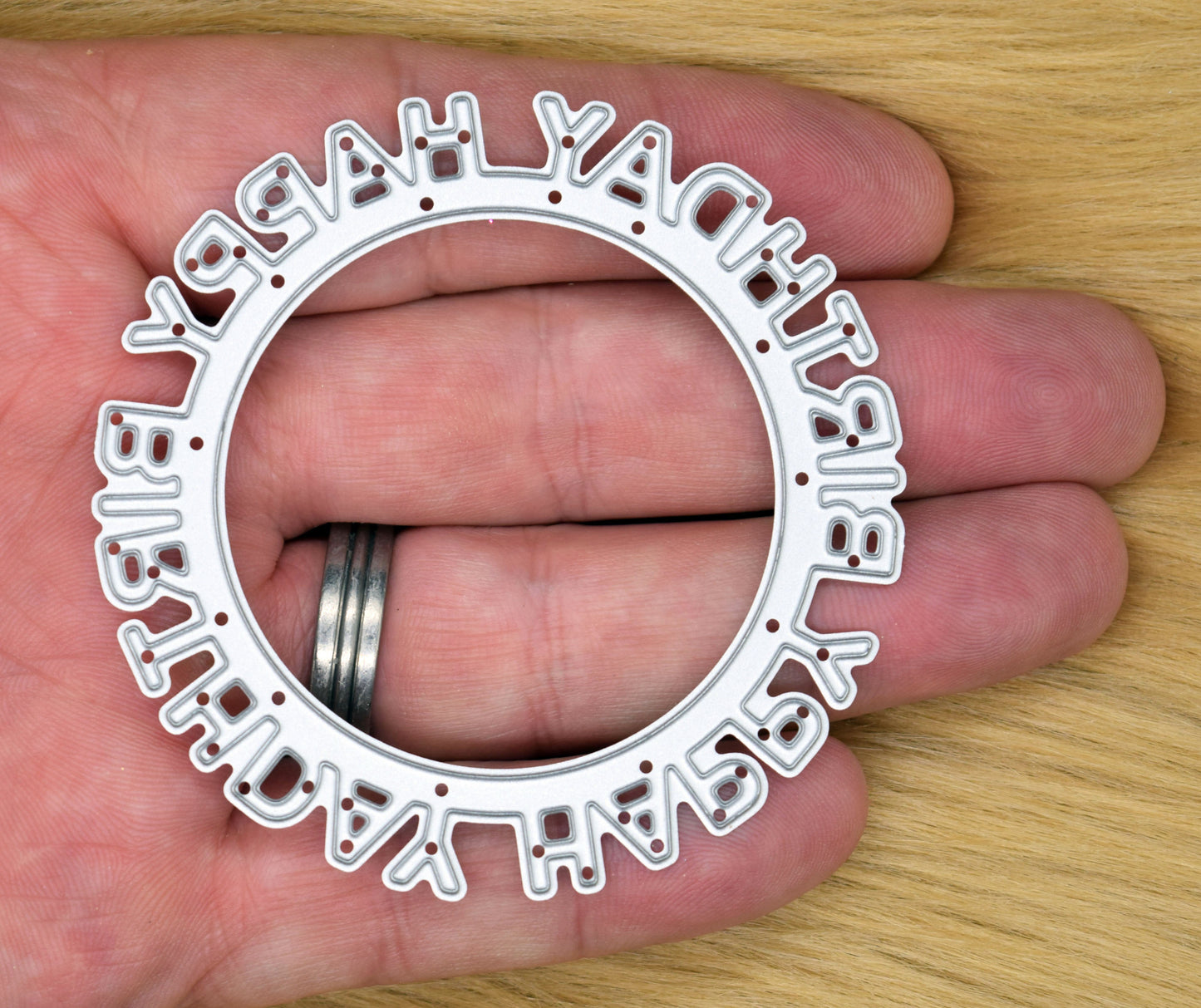 Happy Birthday circular sentiment frame cutting die shown in hand for size reference
