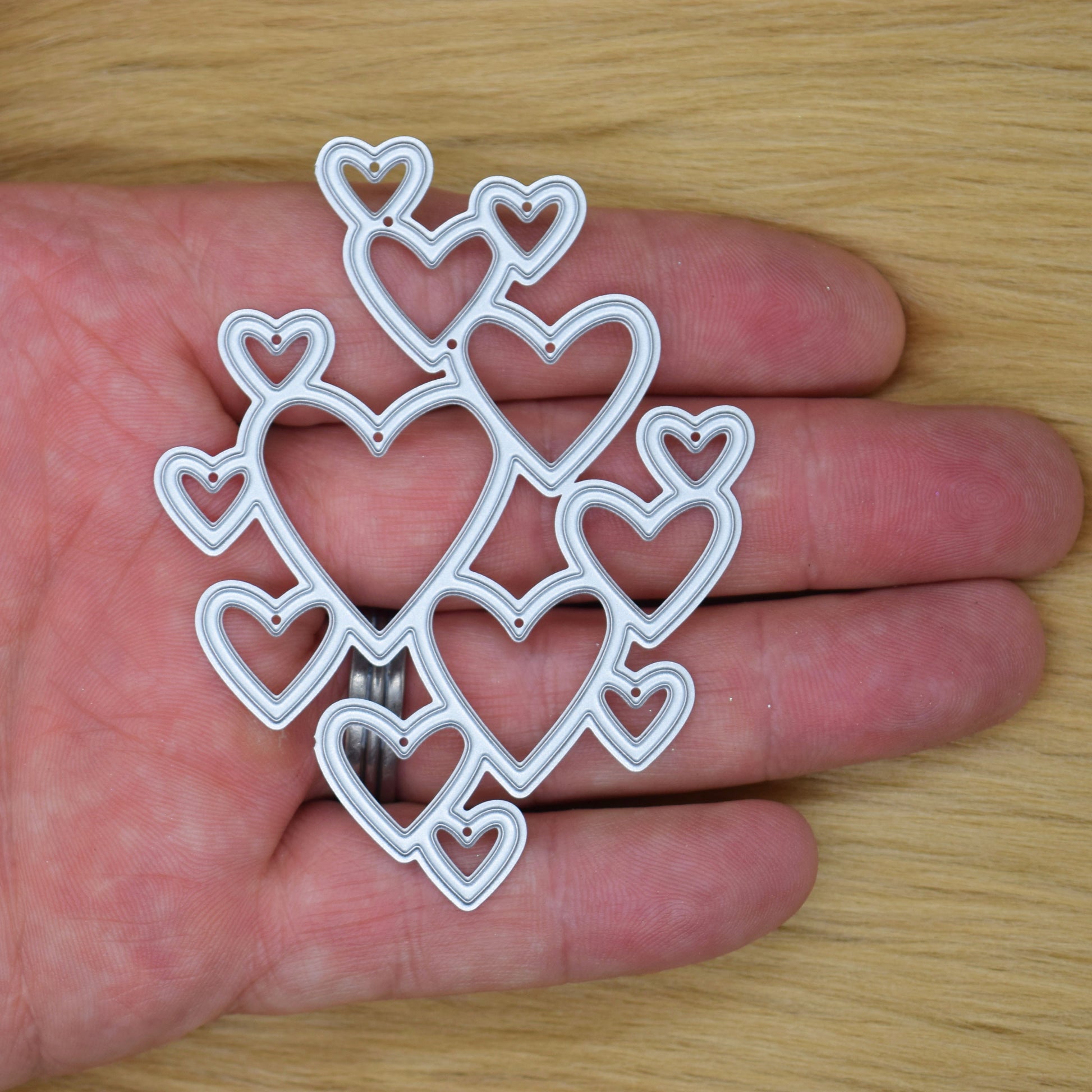 Heart cluster metal cutting die shown in hand for size reference