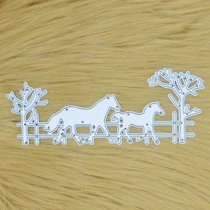 Horse and foal countryside scene metal cutting die with fence and bare trees displayed on a tan faux fur background.