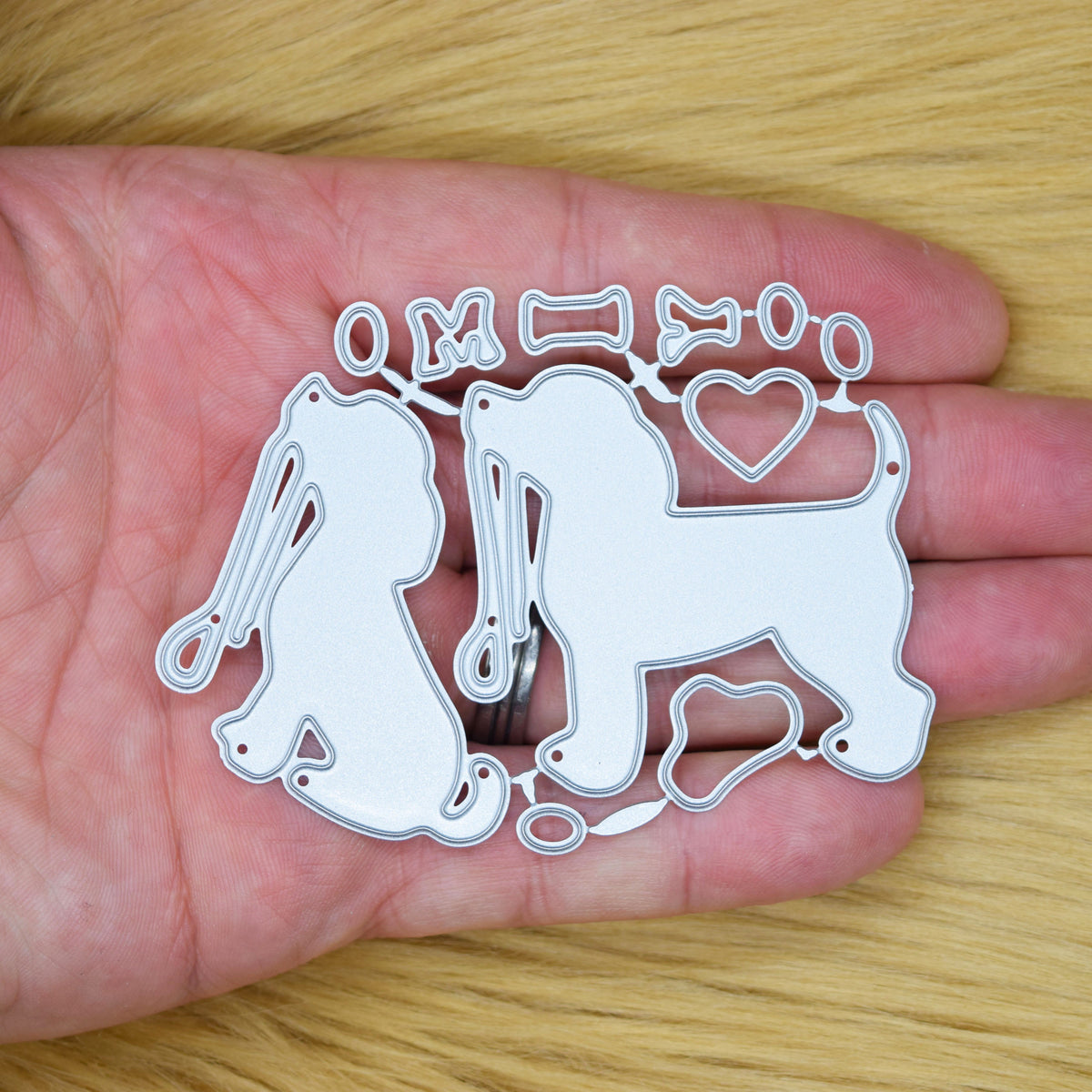 I Love My Dog metal cutting dies held in hand showing the dog, lead, heart, bone and small pet themed pieces.