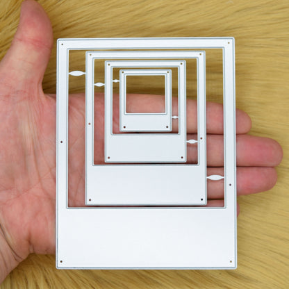 Four graduated instant camera frame nesting metal cutting dies held in hand to show their relative sizes