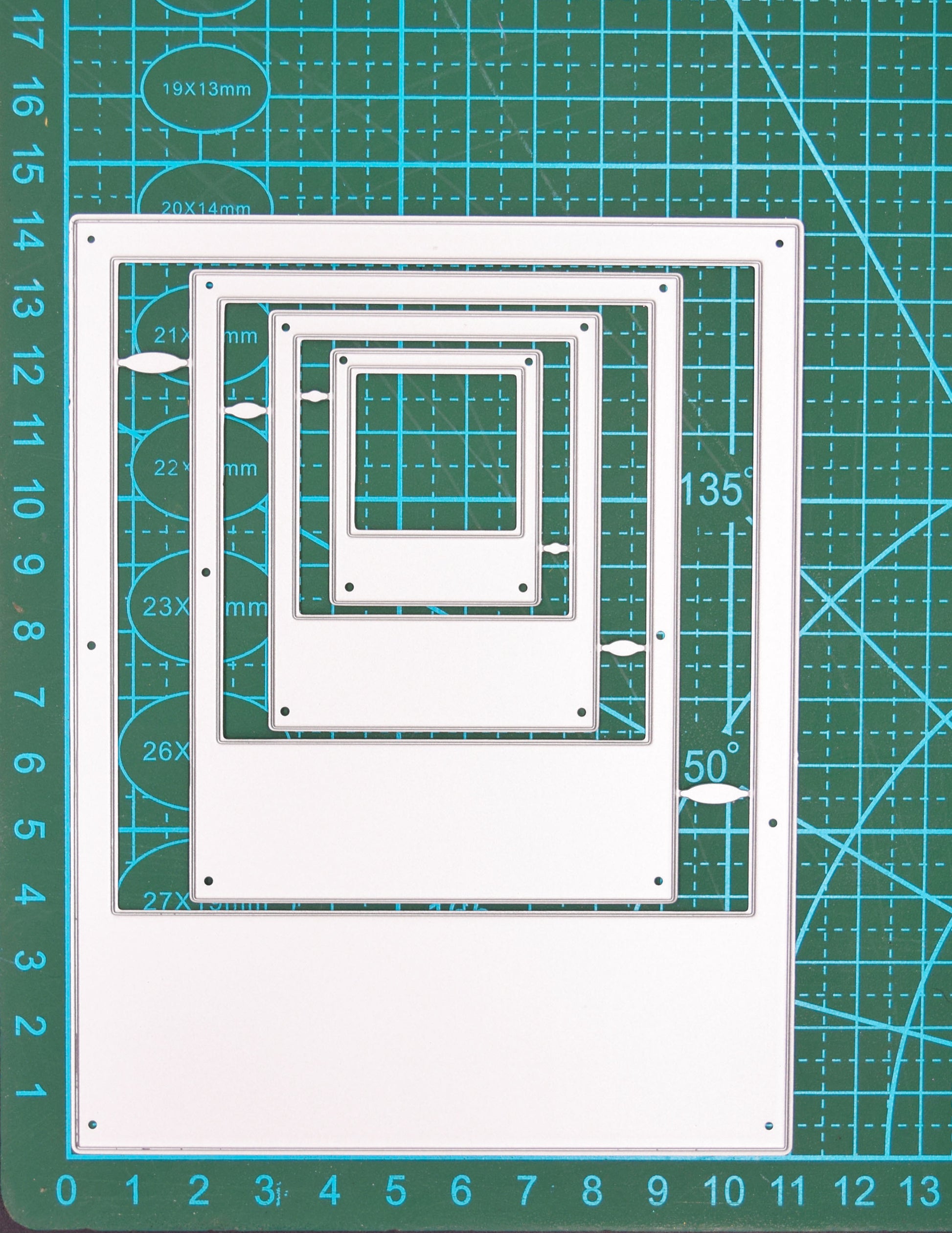 Instant camera frame nesting metal cutting dies shown on a centimetre cutting mat for size reference
