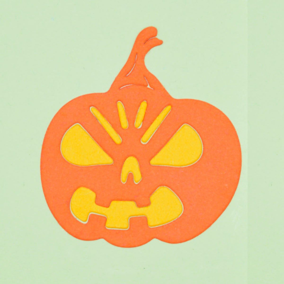 Orange Halloween pumpkin paper die cut with yellow facial inserts, made using a metal cutting die for card making and papercraft.