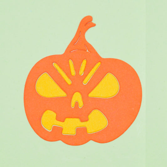 Orange Halloween pumpkin paper die cut with yellow facial inserts, made using a metal cutting die for card making and papercraft.