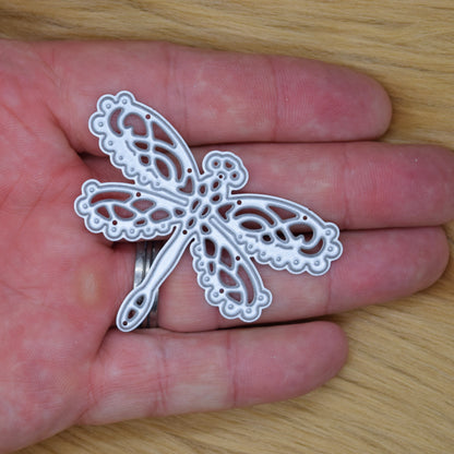 Lace dragonfly metal cutting die shown in hand for size reference and scale for papercraft and card making