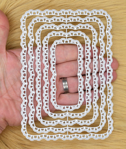 Lace rectangle nesting dies shown in hand for size reference