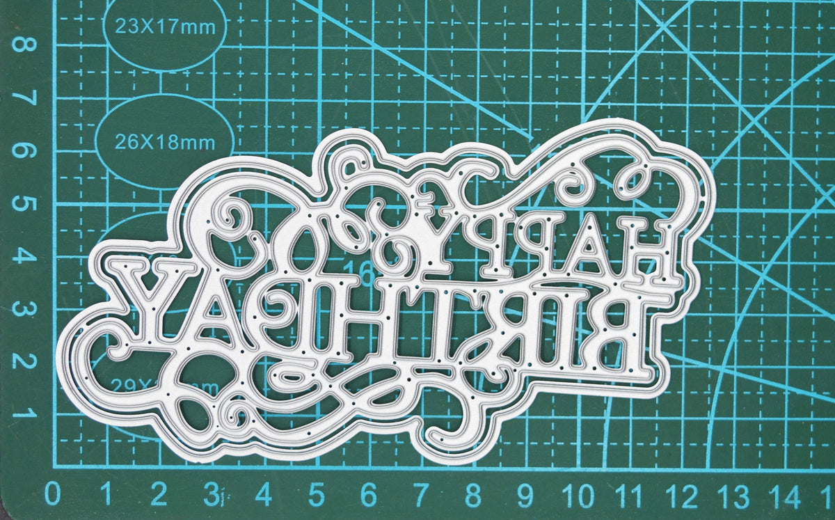 Large decorative Happy Birthday sentiment die photographed on craft cutting mat for size guidance