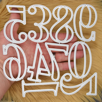 Connected set of large number metal cutting dies held in hand to show the size and decorative numeral designs