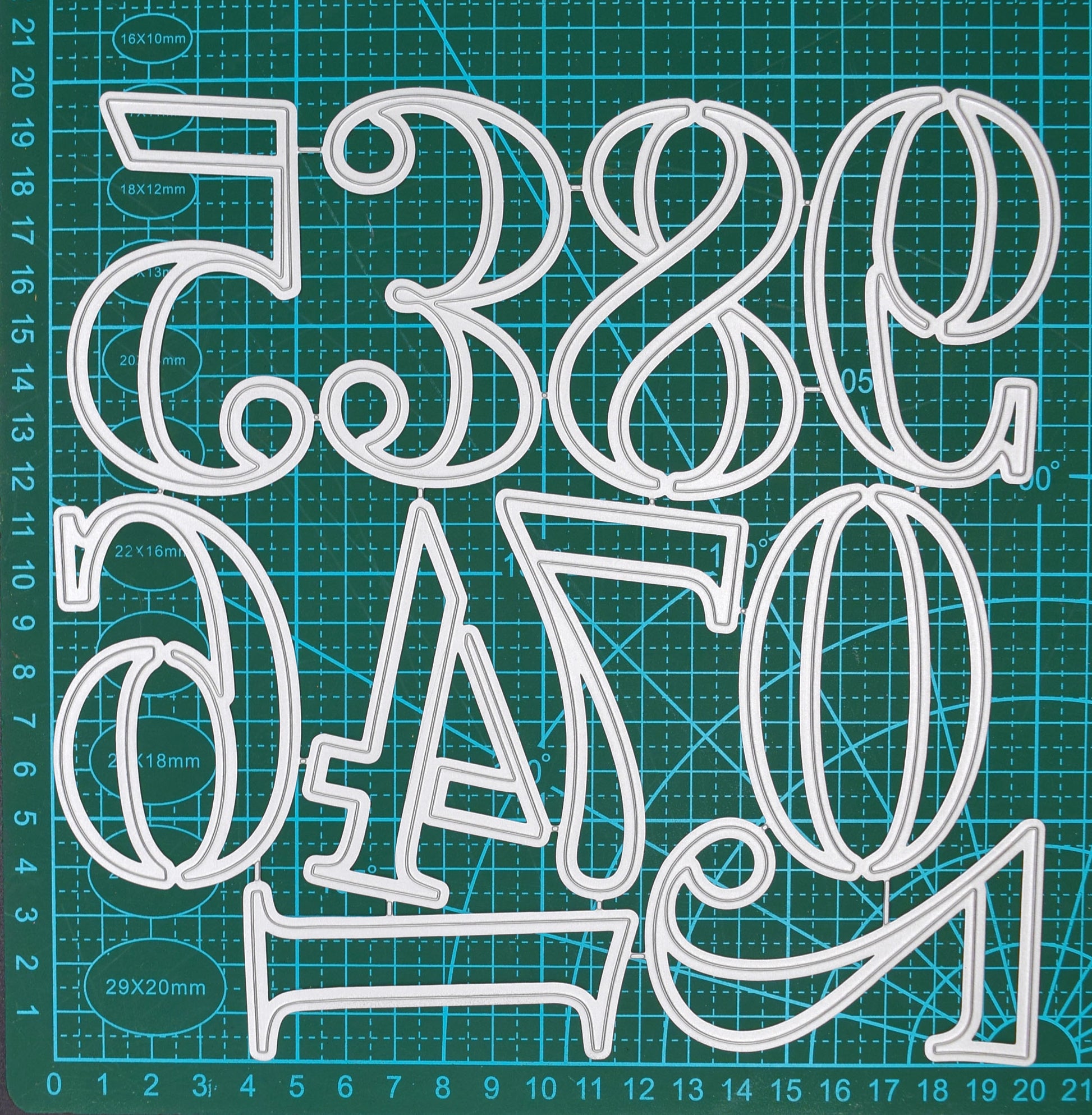 Large number metal cutting dies from 0 to 9 displayed connected on a centimetre cutting mat for size reference