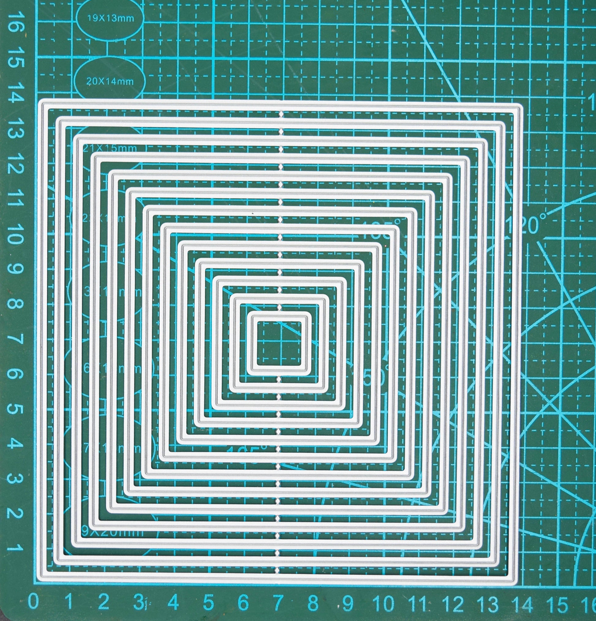 Large square nesting metal cutting dies set on measuring mat showing graduated sizes