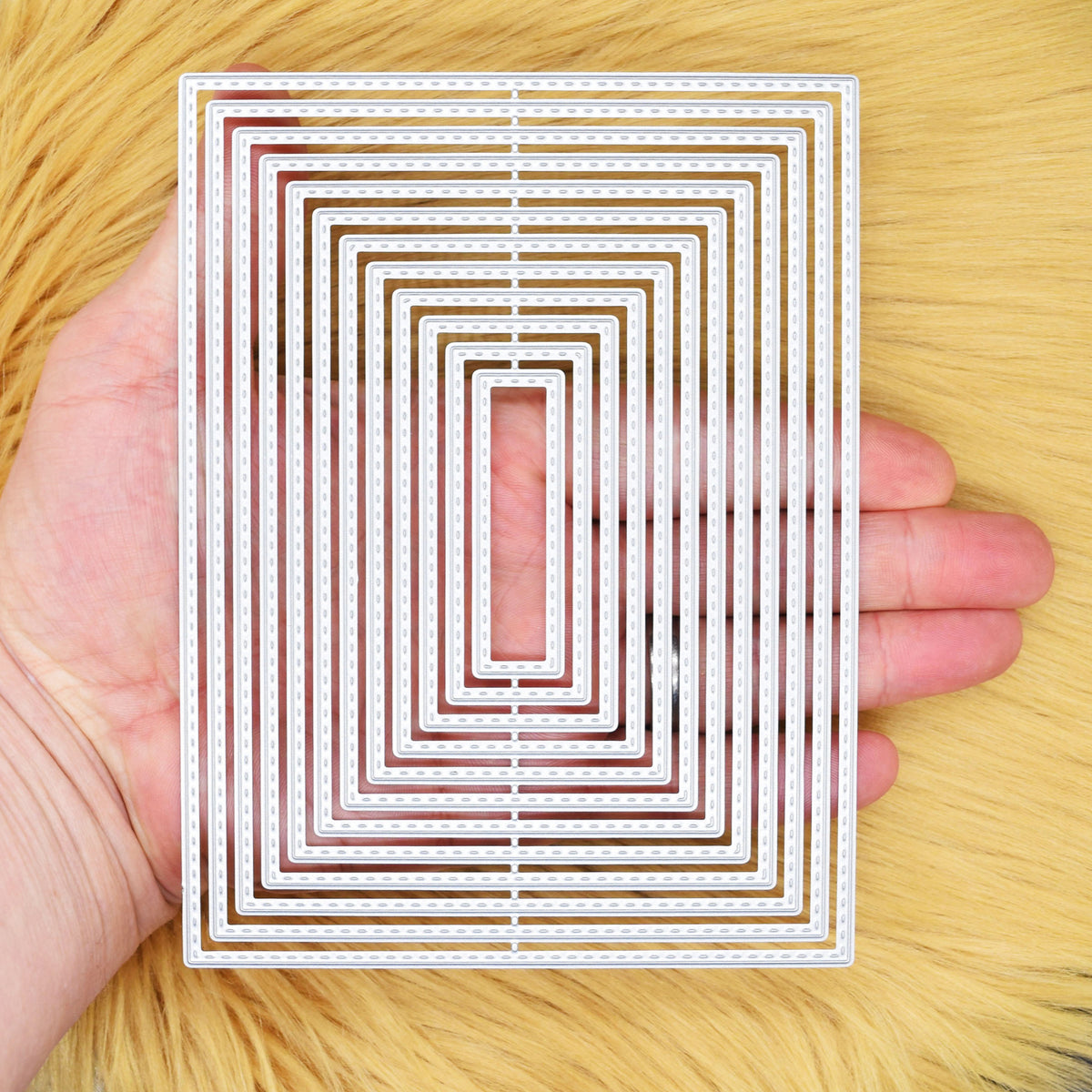 Large stitched rectangle nesting dies held in a hand to show the size of the 12-piece set.