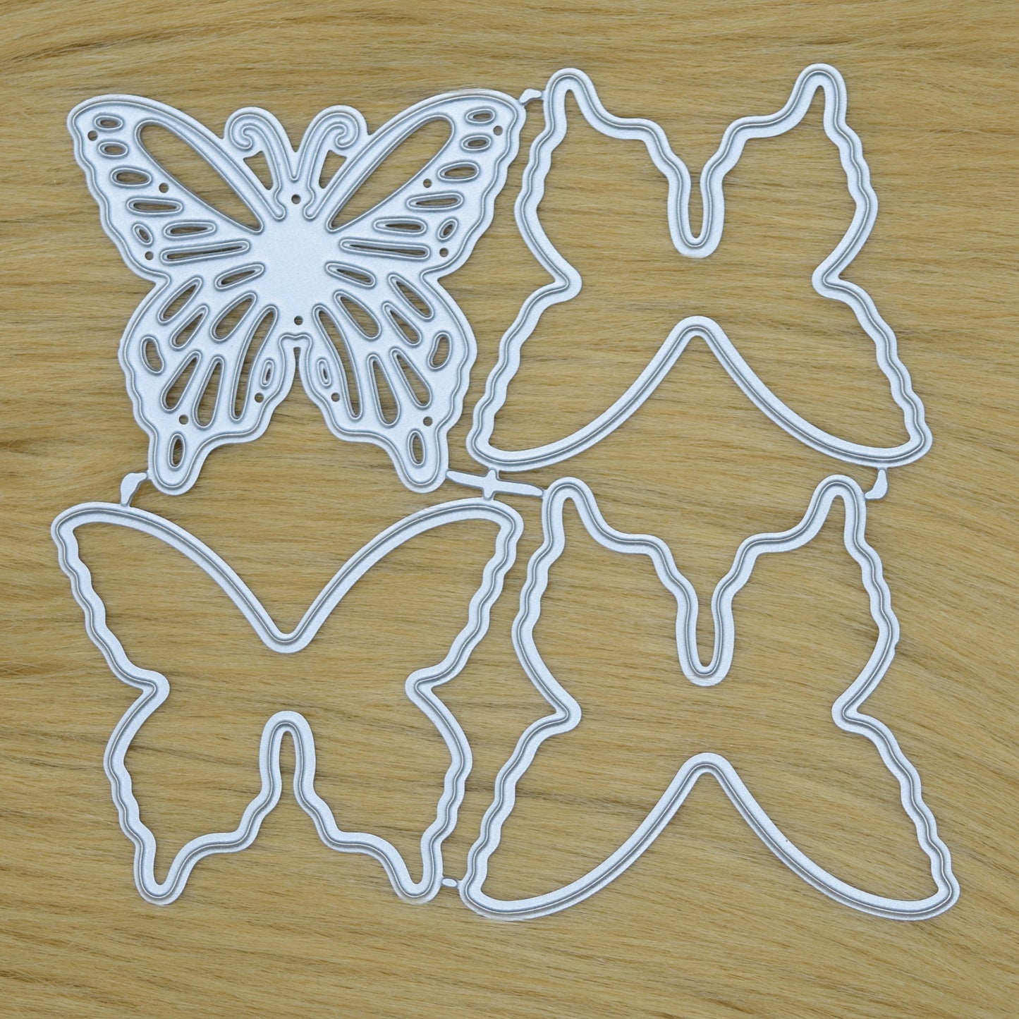 Layered butterfly metal cutting dies set on faux fur background showing all die pieces