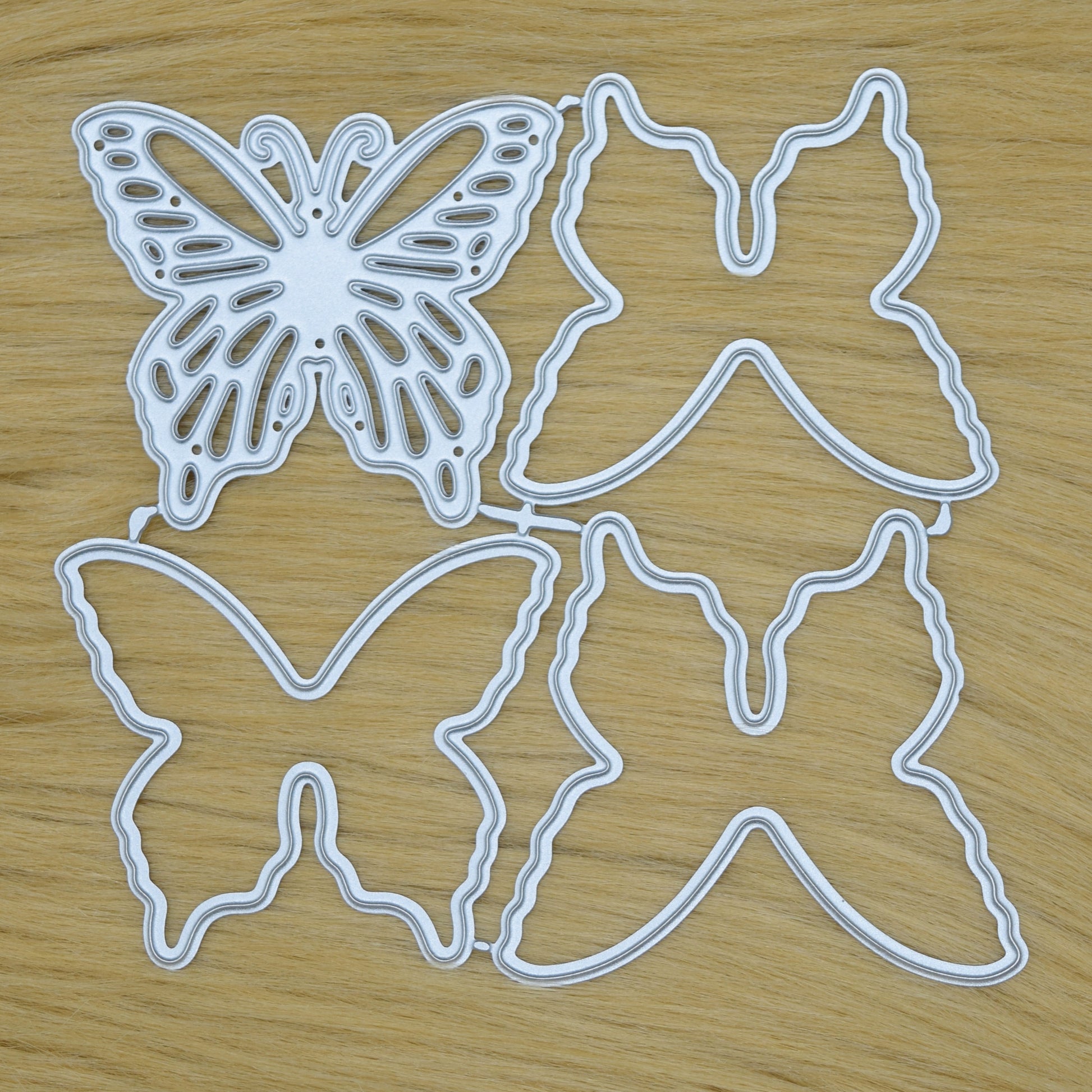 Layered butterfly metal cutting dies set on faux fur background showing all die pieces