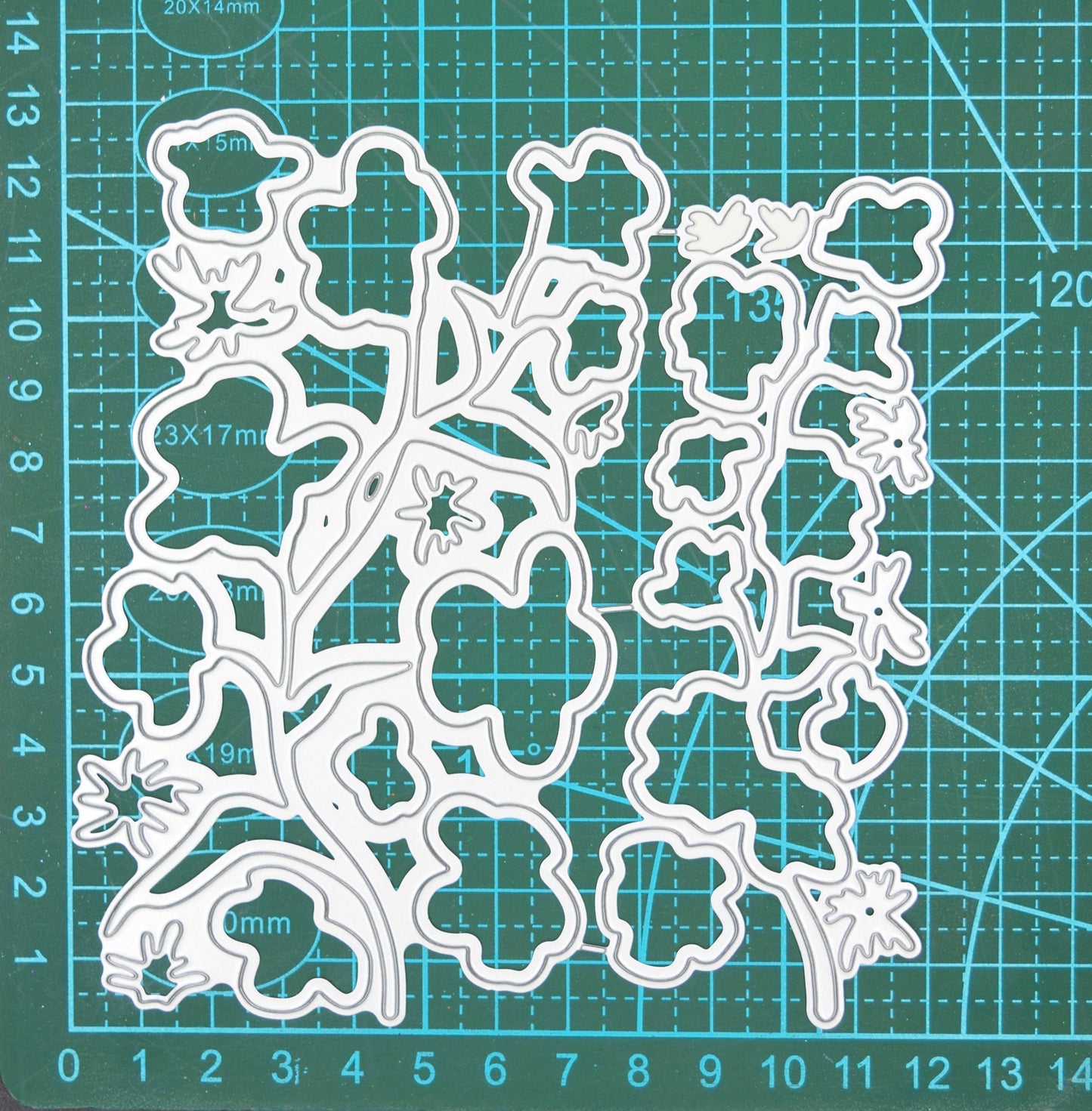 Layered floral stem metal cutting dies on cutting mat showing flower and leaf die sizes for card making
