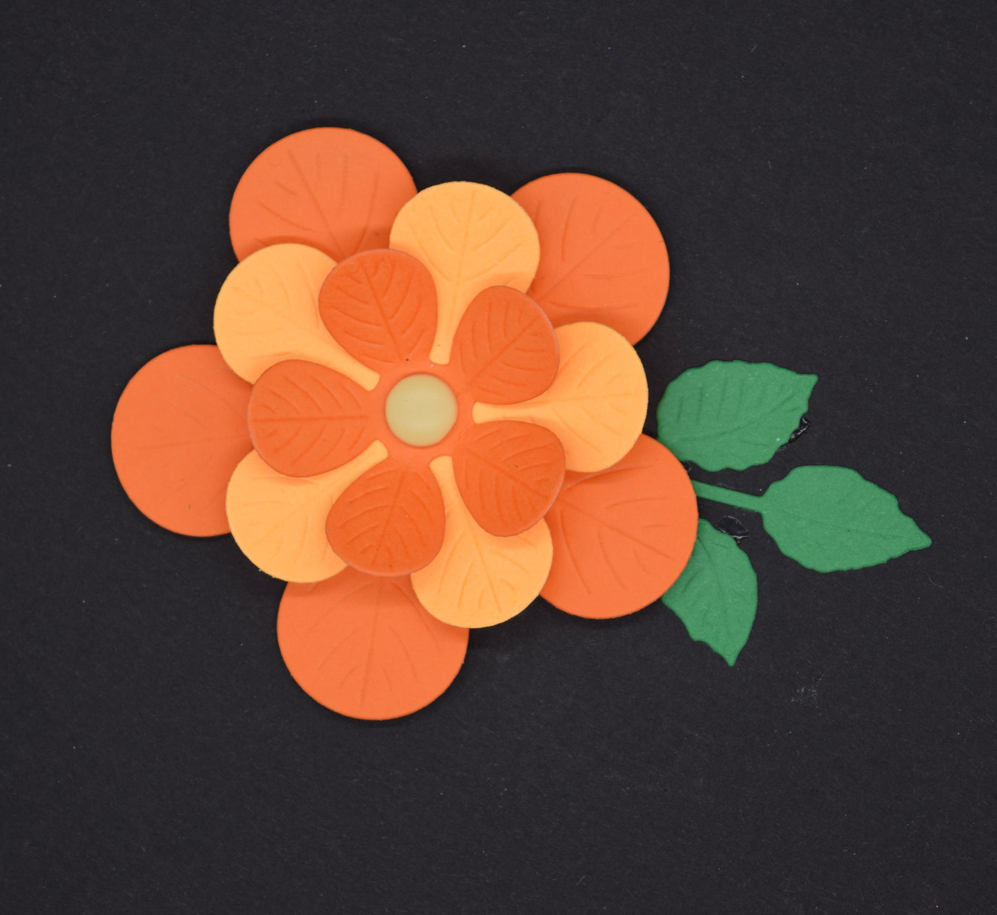 Top view of layered 3D flower die cut with embossed petals and leaf detail