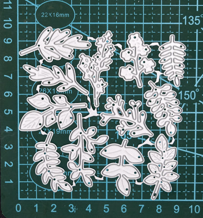 Connected leaf and foliage metal cutting dies displayed on a centimetre cutting mat for size reference