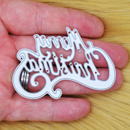 Merry Christmas metal cutting die held in a hand to show its size for Christmas card making.