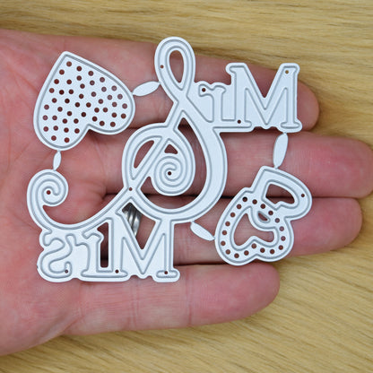 Mr and Mrs metal cutting die shown in hand for size reference featuring decorative hearts and swirled ampersand design