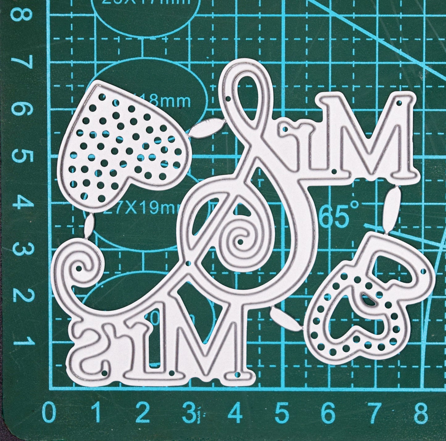 Mr and Mrs metal cutting dies with decorative ampersand and heart designs shown on cutting mat for size reference