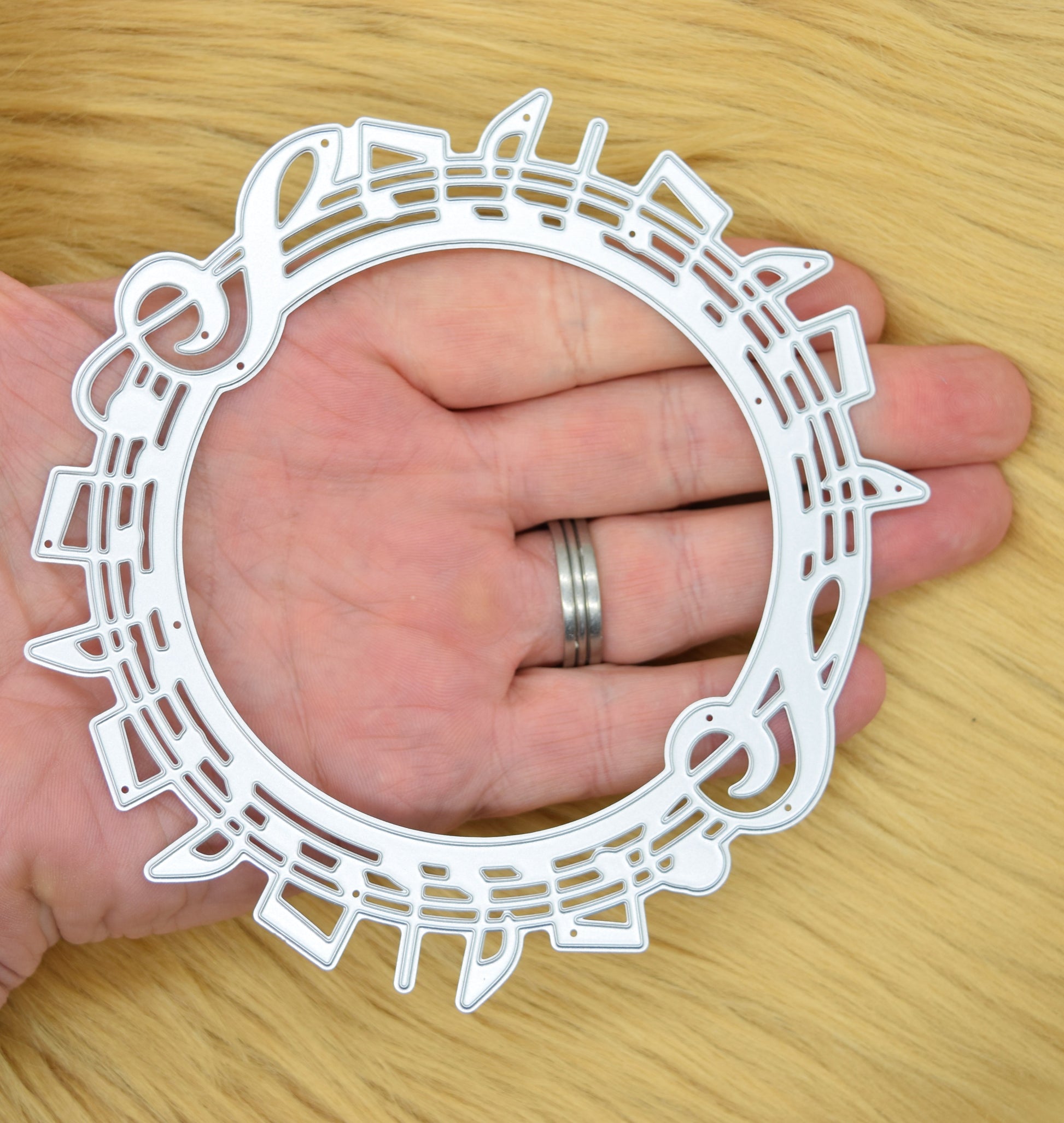 Music notes circle metal cutting die held in hand showing size