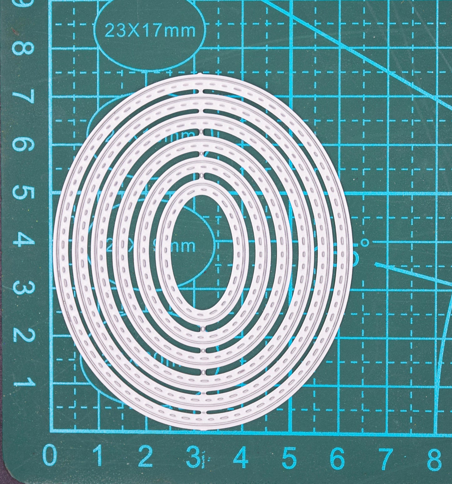 Nesting stitched oval metal cutting dies set shown on cutting mat with measurements for card making and papercraft
