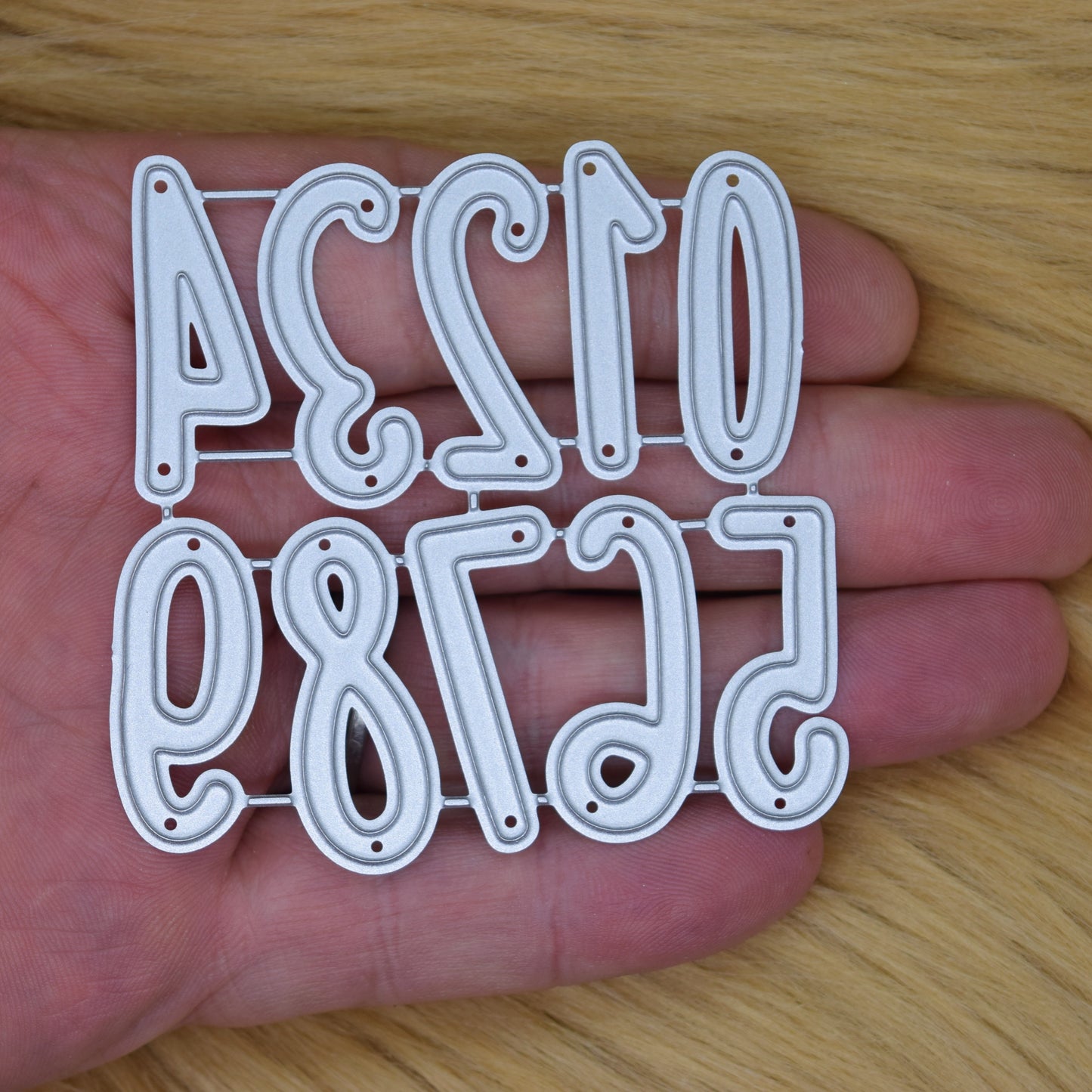 Number metal cutting dies shown in hand for scale reference