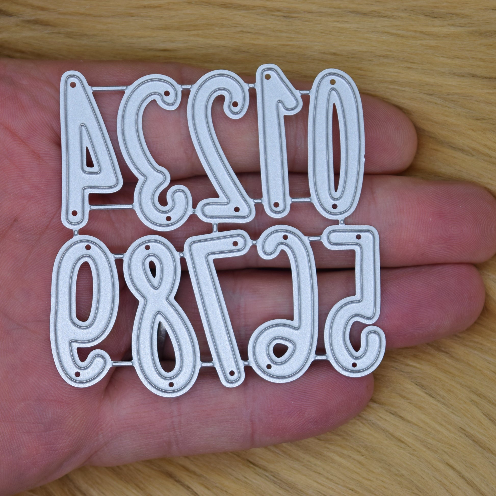 Number metal cutting dies shown in hand for scale reference