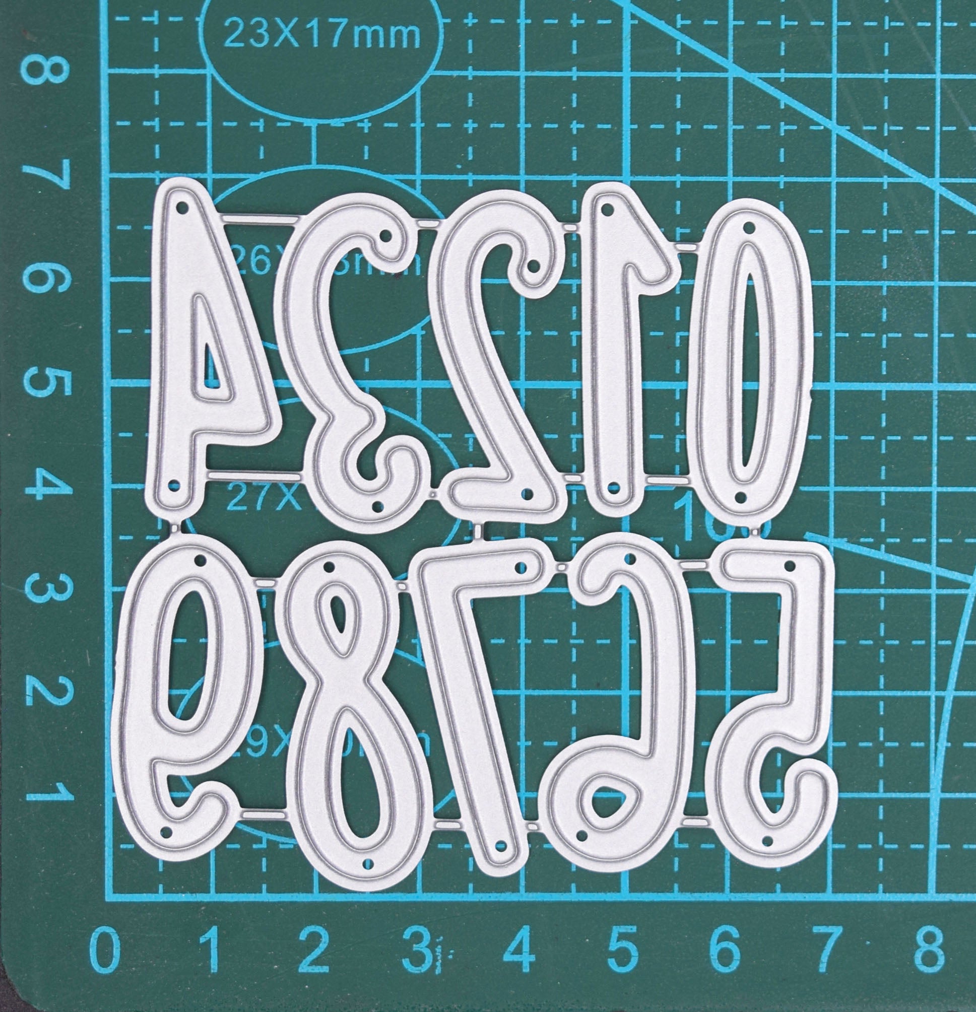 Number metal cutting dies set shown on measuring mat for size reference