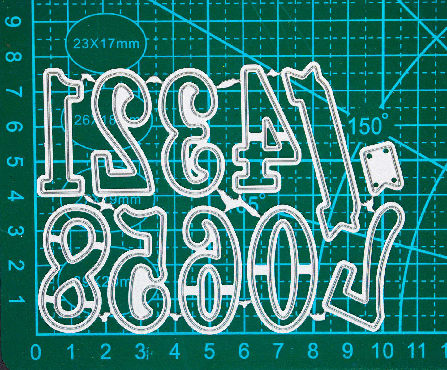 Decorative numbers and banner metal cutting dies displayed on a centimetre cutting mat for size guidance.