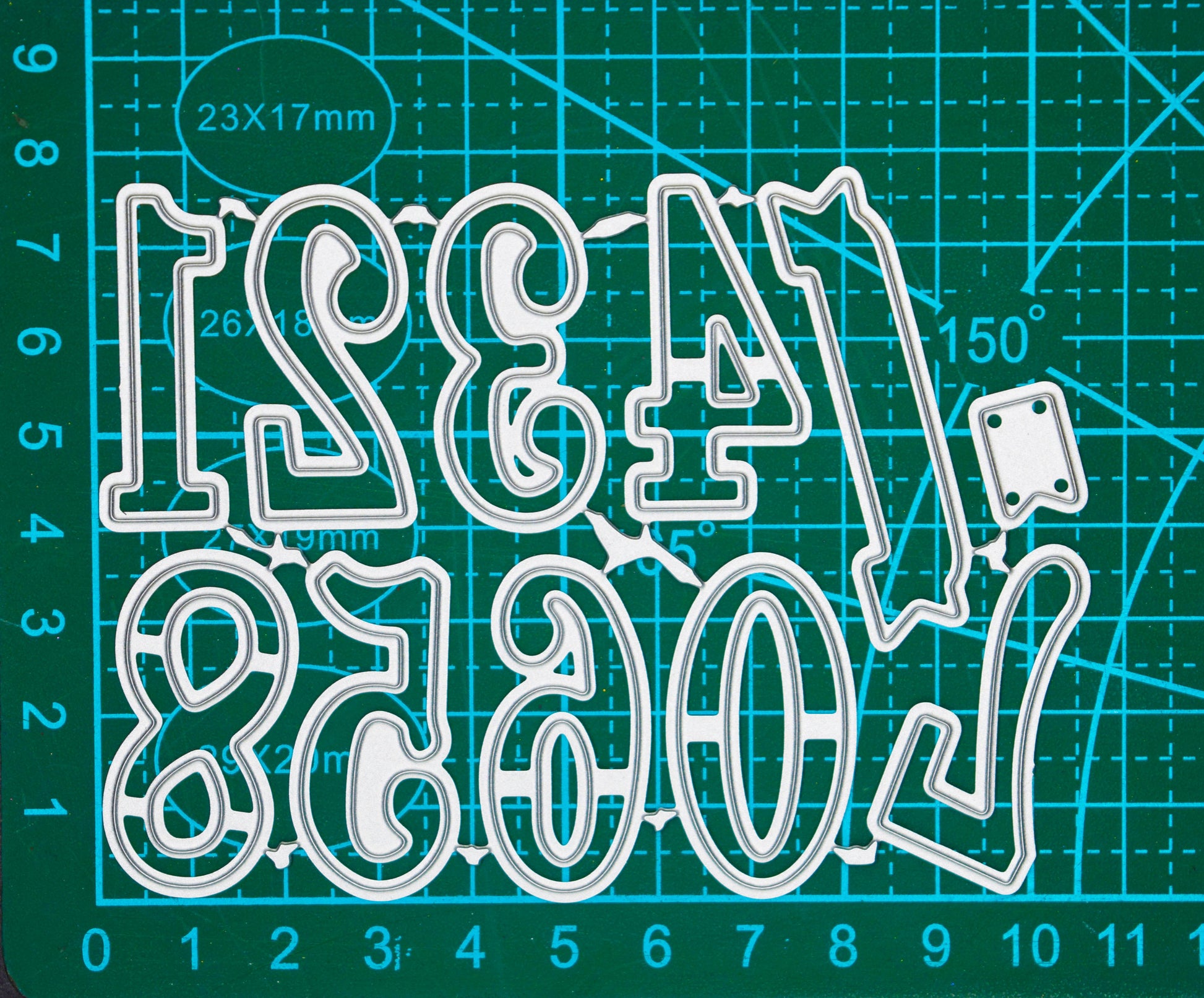 Decorative numbers and banner metal cutting dies displayed on a centimetre cutting mat for size guidance.
