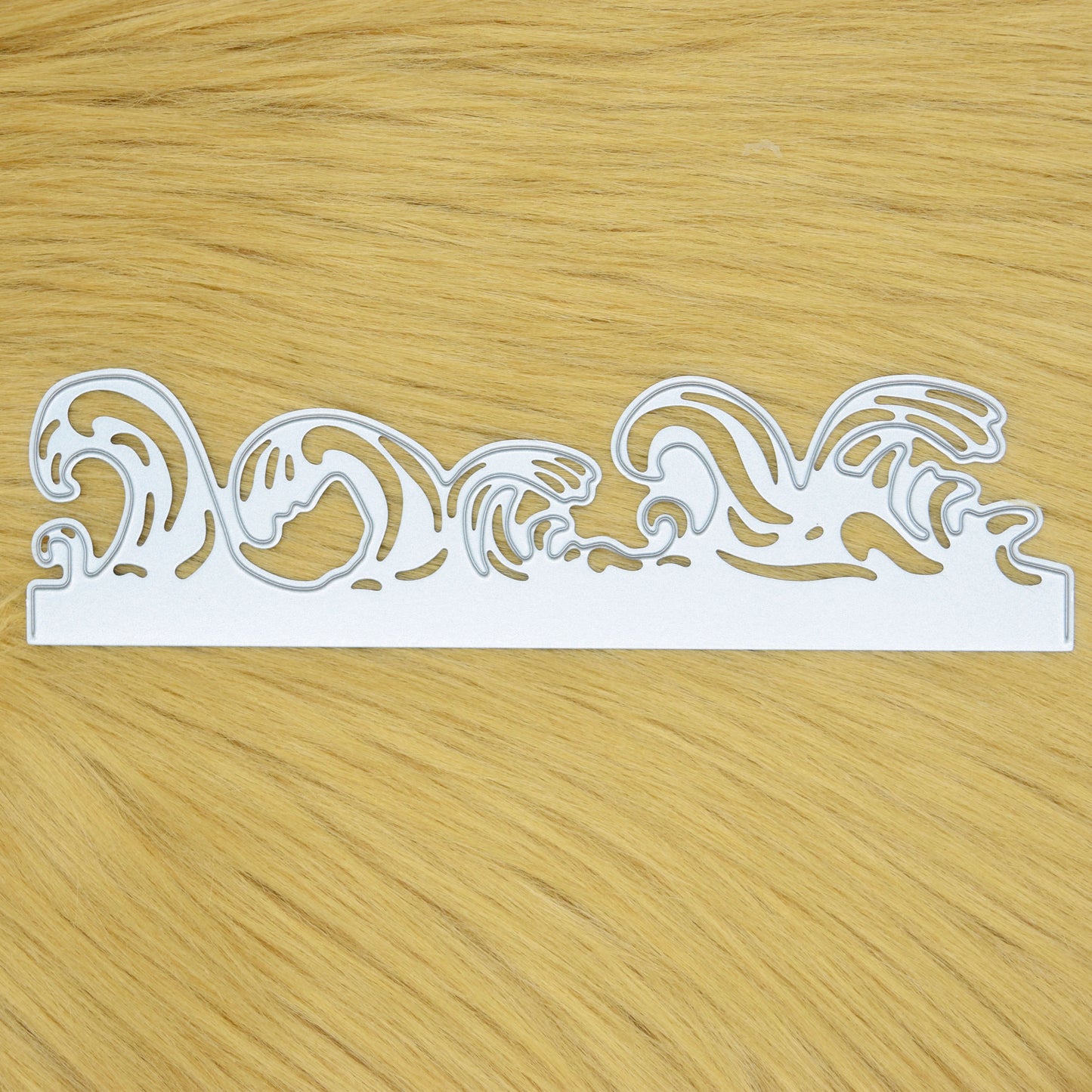 Ocean waves border metal cutting die held in hand to show the size of the decorative edging die