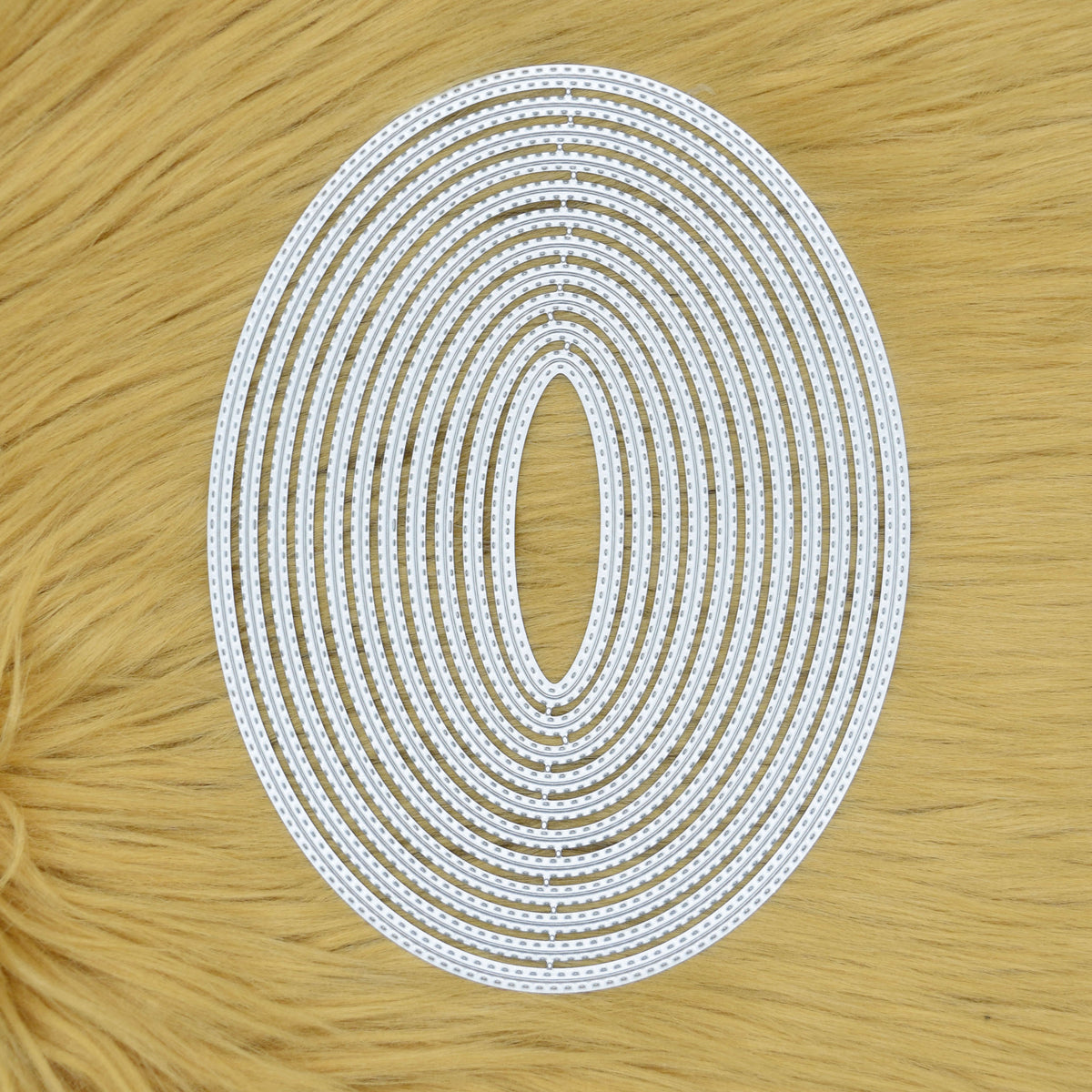 Large double stitched oval nesting metal cutting dies displayed together on a faux fur background.