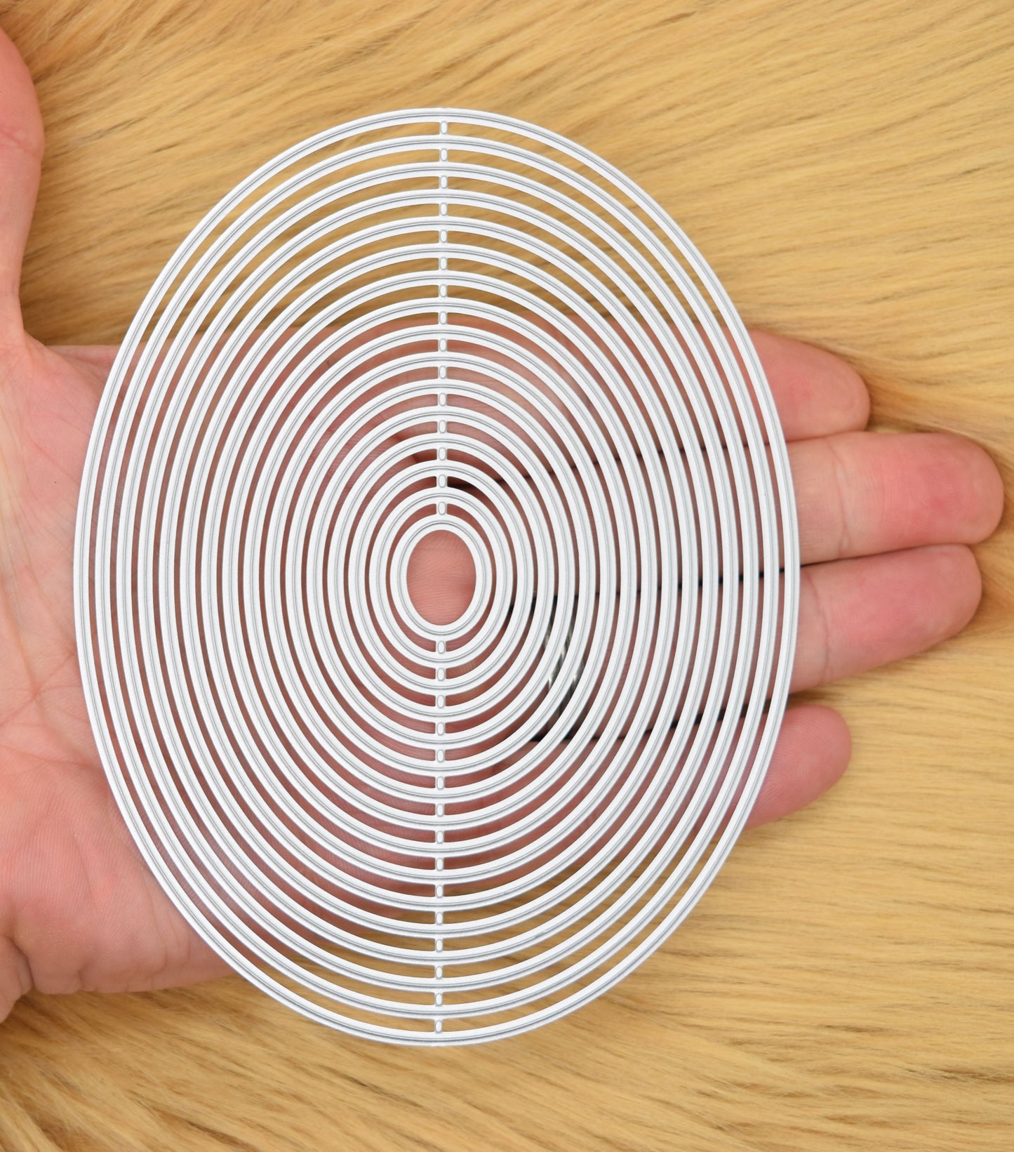 Oval nesting dies set held in hand to show size