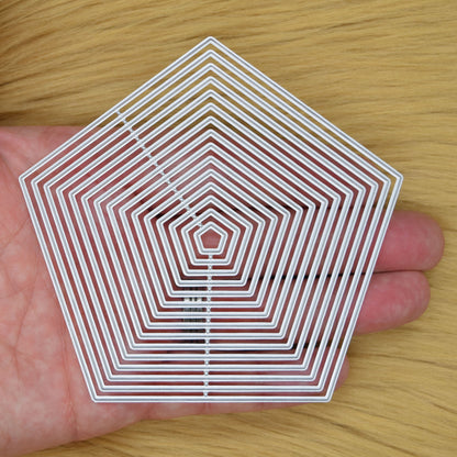 Fifteen pentagon nesting metal cutting dies shown in hand to demonstrate the graduated sizes for handmade cards and craft projects.