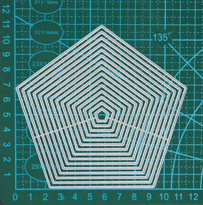 Pentagon nesting metal cutting dies displayed on a centimetre cutting mat to show the graduated sizes for card making and scrapbooking.