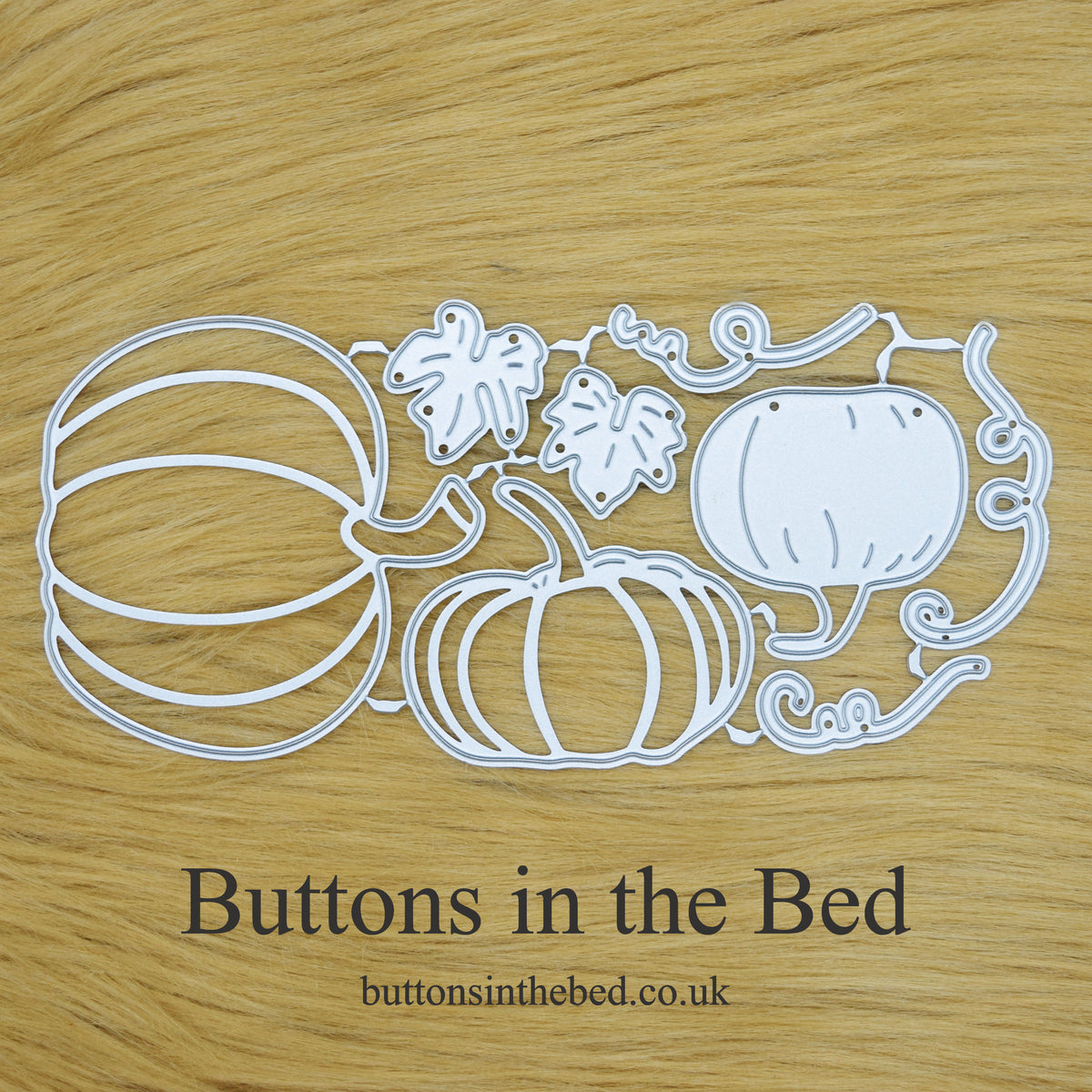 Pumpkin, leaf and vine metal cutting dies arranged on a tan faux fur background with Buttons in the Bed branding.