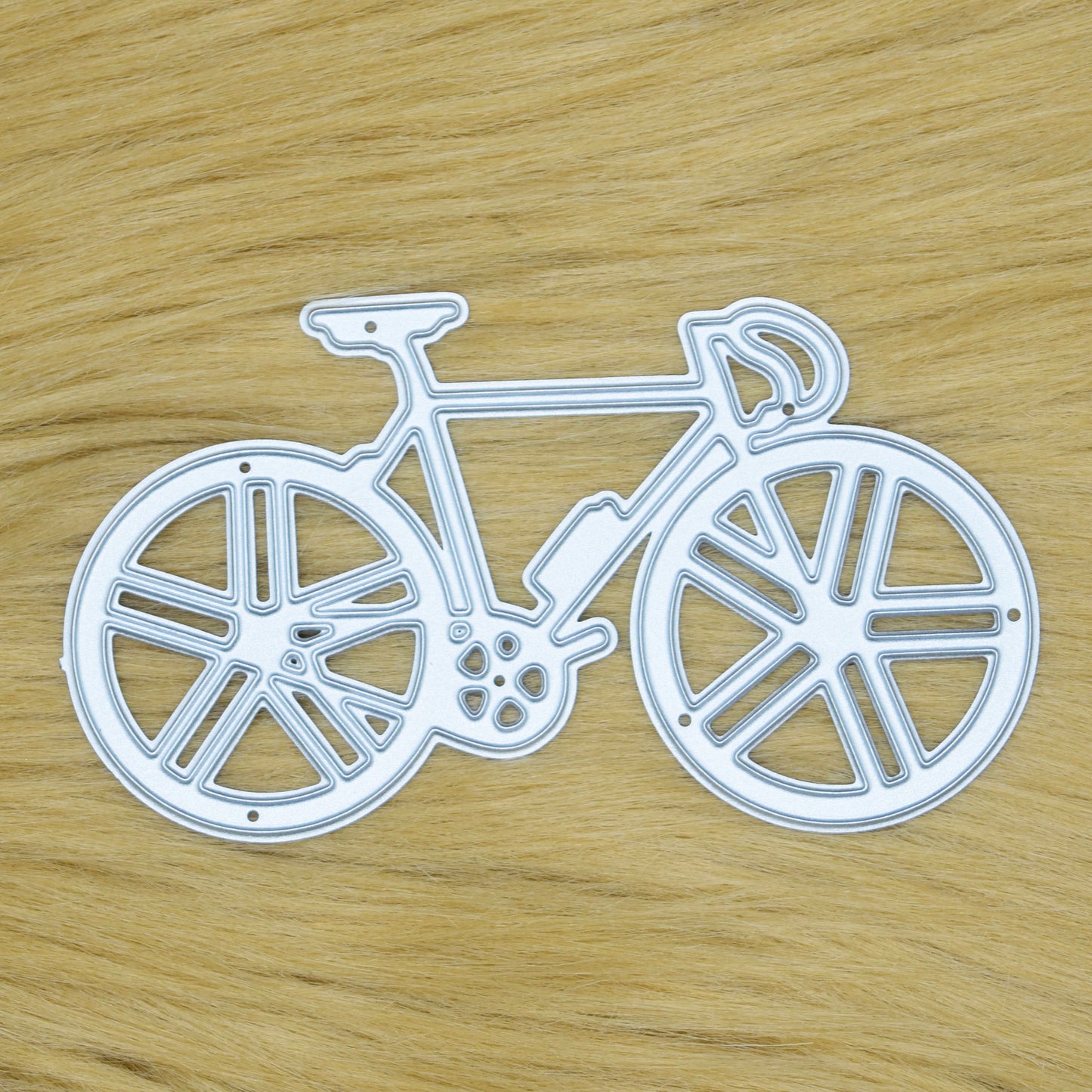 Racing bicycle metal cutting die displayed on a soft faux fur background for card making, scrapbooking and cycling-themed papercraft.
